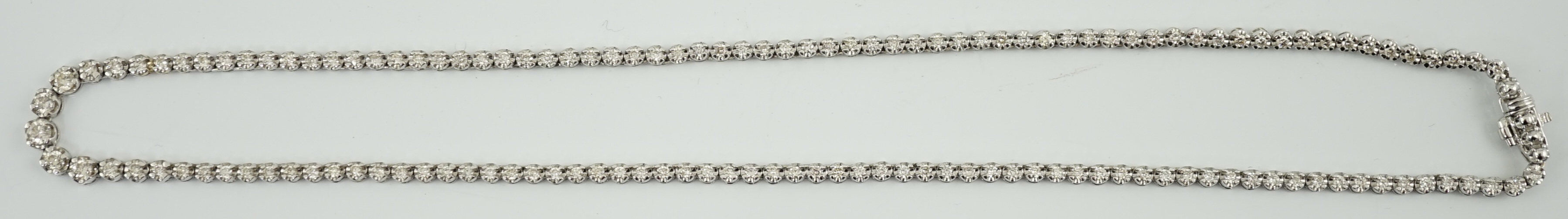 A modern 18k gold and illusion set diamond line necklace, set with diamond chips and five graduated larger stones, 40cm, gross weight 17 grams. Condition - poor to fair (old repair to one link)